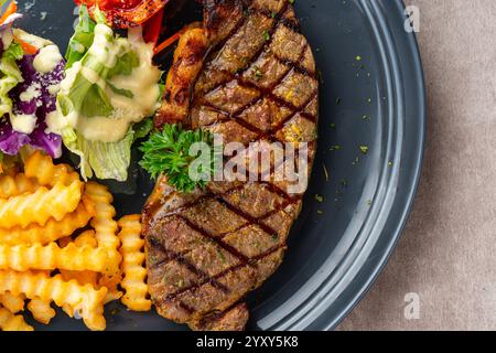 Steak de bœuf d'aloyau grillé avec frites et salades. Banque D'Images