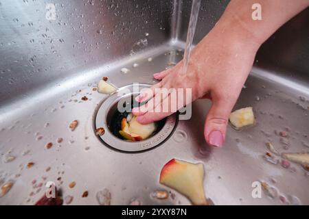 Retirer les déchets alimentaires d'un évier de cuisine avec un broyeur d'ordures et de l'eau courante. Banque D'Images