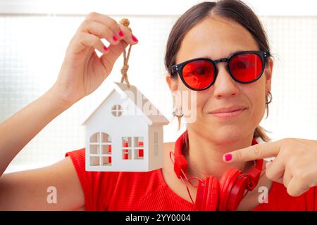 Femme tenant un modèle de petite maison et pointant vers lui Banque D'Images