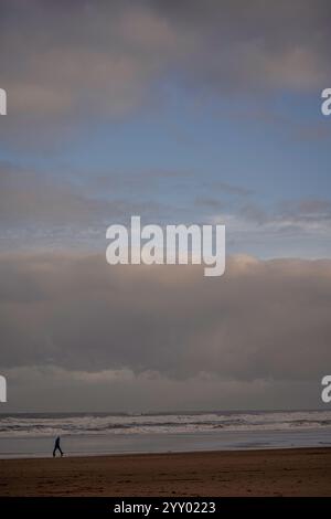 une personne marchant le long d'une plage de sable au bord de la mer à saltburn, yorkshire du nord, angleterre, royaume-uni Banque D'Images