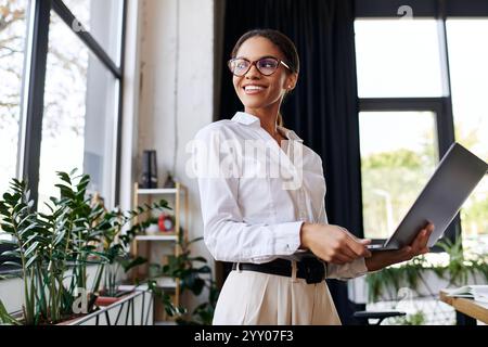 Une jeune femme d'affaires afro-américaine dans une chemise blanche élégante est activement engagée dans son travail. Banque D'Images