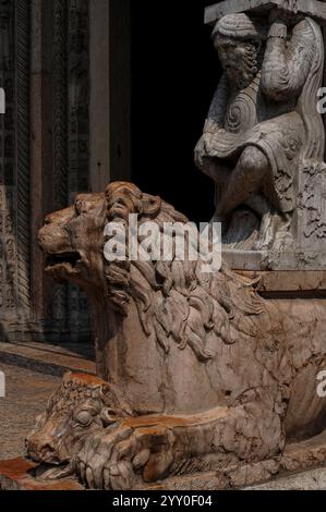 Lion avec tête de veau entre ses pattes et un telamon, sculpté dans les années 1100 À côté de l'entrée principale ouest de la cathédrale Saint-Georges (Duomo di San Giorgio Martire) à Ferrare, Emilie-Romagne, Italie. La partie inférieure de la cathédrale a été construite au XIIe siècle dans un style roman. Banque D'Images