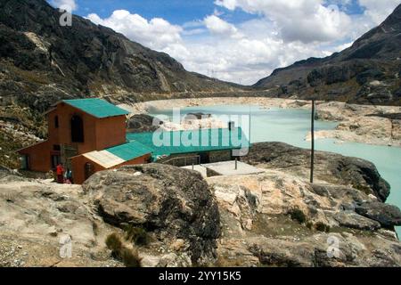 Une vue panoramique d'un bâtiment avec un toit vert situé dans la région montagneuse de Huayna Potosí, Bolivie, près d'un lac turquoise. Banque D'Images