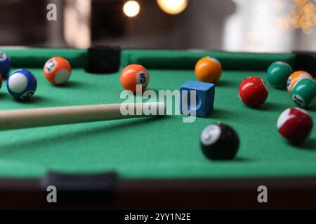 Beaucoup de boules de billard colorées, queue et craie sur la table verte à l'intérieur, gros plan Banque D'Images