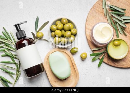 Produits de soins de la peau du corps à l'huile d'olive avec des olives et des feuilles vertes sur fond blanc, pose plate. Spa bio, soin quotidien du corps ou des cheveux, huile d'olive à base d'huile Banque D'Images