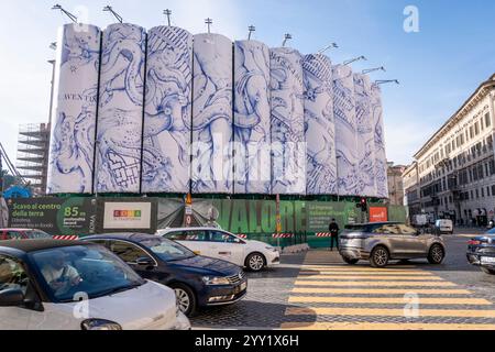 Rome, Italie. 18 décembre 2024. Vue des voitures passant à côté des ''constellations de Rome'', le titre de l'intervention monumentale signée par Pietro Ruffo sur les dix silos qui délimitent le chantier du métro C sur la Piazza Venezia. La première œuvre d’un cycle a été dévoilée, qui dans les prochains mois alternera sur cette nouvelle surface prêtée au contemporain intégré Avec ''murales'', le titre du projet promu par Webuild, une entreprise travaillant à la construction de la ligne C du métro de Rome, le chantier se transforme en une opportunité de régénération urbaine. (Crédit image : © Stefano Costant Banque D'Images