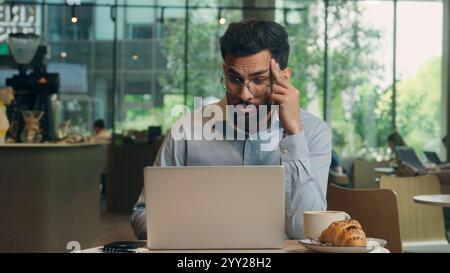 Somnolent fatigué ennuyé homme d'affaires homme d'affaires indien arabe homme d'affaires épuisé gars bouleversé triste mécontent travailleur indépendant visiteur dans le café ennuyeux Banque D'Images
