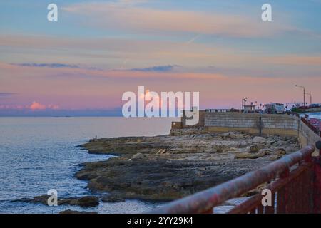 Promenade côtière surplombant Rocky Shoreline au coucher du soleil avec ciel vibrant Banque D'Images