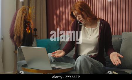 Caucasian souligné femme fille d'affaires freelance mécontent anxieux téléphone mobile parlant à la maison travail à distance étudiante écrivant dans un cahier Banque D'Images