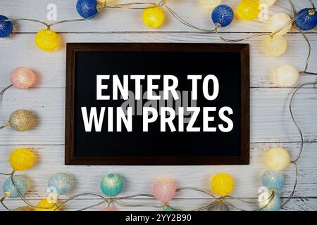 Entrez pour gagner des prix texte écrit sur tableau noir avec décoration de boules de coton LED sur fond en bois Banque D'Images