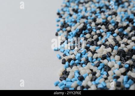 Pile de granulés de plastique colorés sur fond gris, gros plan. Espace pour le texte Banque D'Images