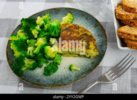 Sur l'assiette est un morceau triangulaire d'omelette avec des taches d'asperges, garni de chou brocoli. Banque D'Images