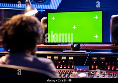 Producteur de musique fonctionne sur le pupitre de commande et l'ordinateur maquette dans le studio professionnel, en appuyant sur les boutons et faders de touche pour créer des sons. Jeune concepteur sonore éditant de la musique et ajoutant des effets audio. Banque D'Images