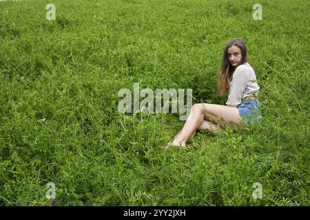 Une jeune femme assise dans un champ de vestes. Banque D'Images