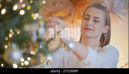 Gros plan sur les mains d'une femme mettant une boule de Noël Banque D'Images