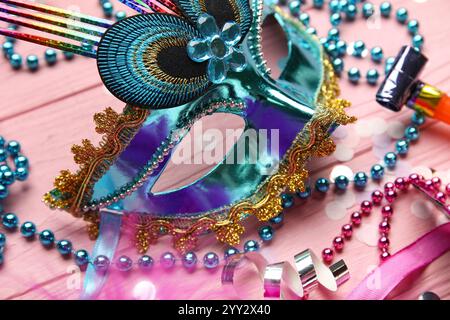 Beau masque de carnaval avec cornes de fête, confettis et perles sur fond de bois rose. Gros plan Banque D'Images