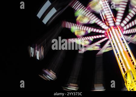 Une image floue d'un tour à un carnaval. Le manège tourne et a des lumières dessus. La scène est énergique et excitante Banque D'Images