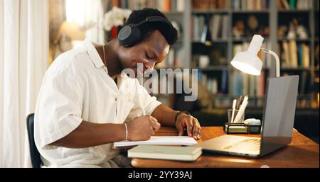 Homme noir, écouteurs et écriture avec étudier, à la maison et heureux pour l'apprentissage à distance, le développement ou la recherche. Personne, notes et livres avec musique Banque D'Images