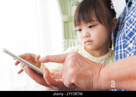 Enfant utilisant un téléphone avec grand-mère Banque D'Images