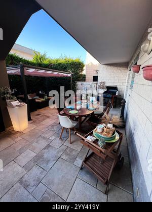 Un espace salle à manger extérieur confortable avec une table en bois pour les invités, entouré de plantes et de décoration. Idéal pour les réunions intimes ou les soirées relaxantes Banque D'Images