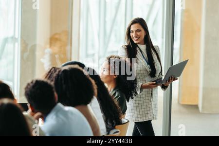 Une femme PDG dirige en toute confiance une réunion d'affaires avec divers professionnels. L'atmosphère est collaborative et innovante, mettant l'accent sur le leade moderne Banque D'Images