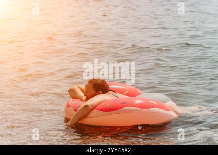 Flotteur gonflable homme Summer Vacation Water - Un homme se détend sur un flotteur gonflable dans l'eau pendant des vacances d'été. Banque D'Images