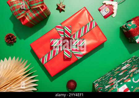 Un gros plan de cadeaux de Noël magnifiquement emballés en rouge et vert avec des rubans et des noeuds des éléments festifs comme des ornements, des pommes de pin et un décorati Banque D'Images