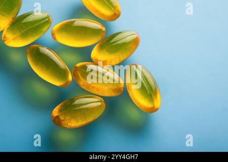 Une image rapprochée de capsules de gel transparentes dispersées sur un fond bleu la couleur jaune or vif des capsules contraste nettement avec le Banque D'Images