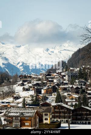 Un pittoresque village suisse niché sous un paysage alpin enneigé, présente de charmants chalets sur fond de sommets majestueux. Banque D'Images