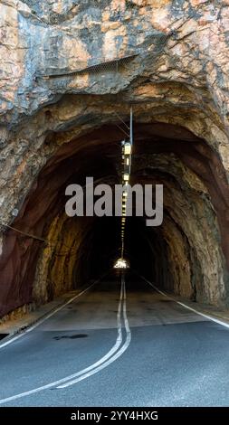 Une vue panoramique d'un tunnel rocheux avec des plafonniers à Majorque, Espagne la route courbe disparaît dans l'obscurité, offrant un sentiment de mystère et d'adve Banque D'Images