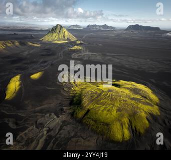 Vue aérienne captivante sur le terrain volcanique de l'Islande, avec des champs de lave couverts de mousse et des montagnes lointaines, mettant en valeur les spectaculaires paysages naturels de l'île Banque D'Images