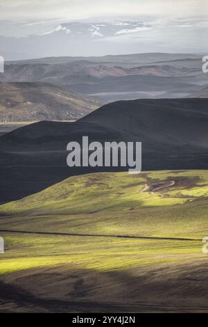 Une vue imprenable sur le vaste paysage de l'Islande avec des collines volcaniques ondulantes et des montagnes lointaines, mettant en valeur la beauté naturelle étonnante de l'île Banque D'Images