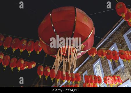 Un spectacle éblouissant de lanternes rouges traditionnelles suspendues au-dessus d'une rue nocturne, illuminant les environs d'une lueur chaleureuse, évoquant une ambiance festive et festive Banque D'Images