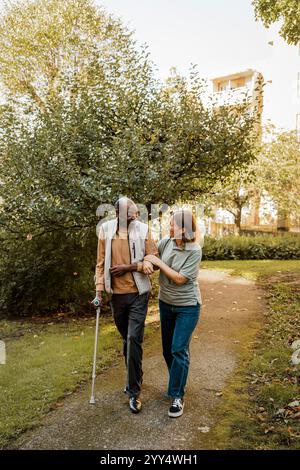 Infirmière et homme senior marchant bras dans bras sur le sentier pédestre au parc Banque D'Images