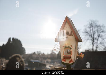 Nichoir en bois orné de fleurs colorées et de champignons fantaisistes, niché dans un jardin serein pendant la saison hivernale tranquille Banque D'Images