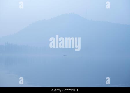 Un batelier cachemirien ramène son bateau à travers le célèbre lac Dal lors d'un matin d'hiver froid et brumeux à Srinagar. La vallée du Cachemire s'enroule actuellement dans des conditions de froid intense alors que la température minimale a chuté de plusieurs degrés en dessous du point de congélation. La capitale de la région, Srinagar, enregistre la nuit la plus froide de la saison à moins 6 degrés Celsius (21,2 degrés Fahrenheit), une fine couche de brouillard également observée dans de nombreuses parties de la vallée. Le bureau météorologique local a prédit un temps principalement sec jusqu'en décembre 26 avec une possibilité de chutes de neige légères dans les tronçons plus élevés de la région résistante de l'Himalaya Banque D'Images