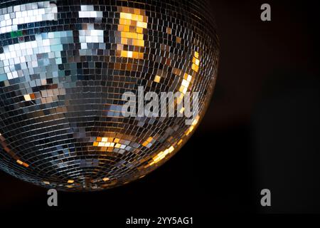 Gros plan sur boule disco brillante avec des rayons lumineux sur fond sombre. Banque D'Images
