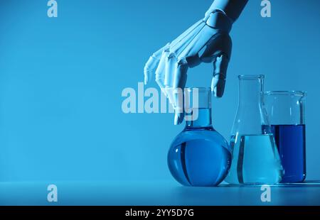 Intelligence artificielle. Main de robot et verrerie de laboratoire avec des liquides à table en lumière bleue, espace pour le texte Banque D'Images