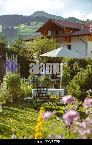 Un coin jardin confortable avec un ensemble de chaise d'extérieur classique et table dans un hôtel, avec montagne en arrière-plan, Dolomites, Italie Banque D'Images