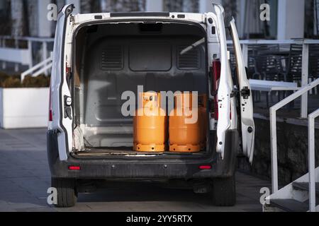 Bouteilles de gaz orange transportées à l'intérieur d'une camionnette. Bouteilles de butane de gaz dans le camion prêt pour la livraison. Véhicule livrant des marchandises dangereuses, gaz comprimé Banque D'Images