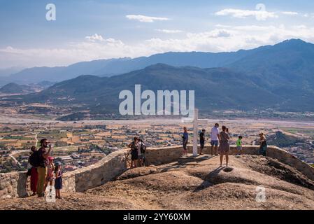 Mystérieux suspendu au-dessus des rochers monastères de Météores, Grèce. Touristes debout à côté de la grande croix blanche, près du monastère de la Sainte Trinité Banque D'Images