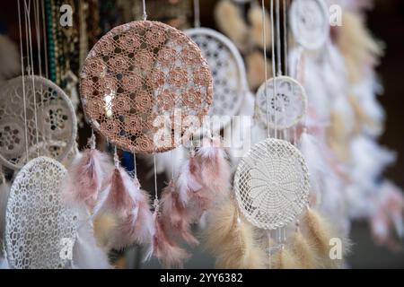 Vue rapprochée de beaucoup de beaux Dreamcatcher avec beaucoup de plumes, suspendu à un plafond de marché étal sur la rue. Attrape-rêves tricoté à la main. Banque D'Images