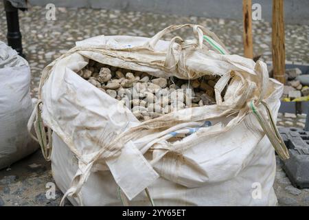 Les sacs blancs de pierres concassées sont dans une rangée, matériau de construction dans le paquet. Pierres pour réparer la route. Un tas de pavés et de cailloux dans un grand sac Banque D'Images
