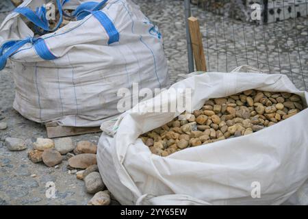 Les sacs blancs de pierres concassées sont dans une rangée, matériau de construction dans le paquet. Pierres pour réparer la route. Un tas de pavés et de cailloux dans un grand sac Banque D'Images