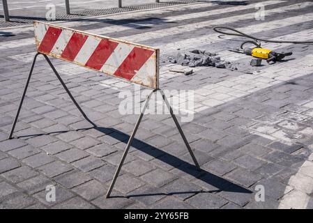 Une pierre a été enlevée d'un passage pour piétons avec une perceuse à percussion rotative électrique. Gros plan. Zone de construction ou travaux routiers sur la rue de la ville. Banque D'Images