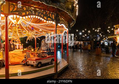 Bâle, Suisse - 5 décembre 2024 : marché de Noël traditionnel le soir avec lumières festives et carrousel manège Banque D'Images