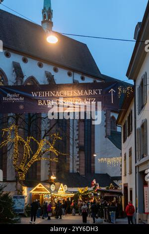 Bâle, Suisse - 5 décembre 2024 : marché de Noël traditionnel en soirée sur la Barfusserplatz avec lumières festives et cabines de rue et vis Banque D'Images