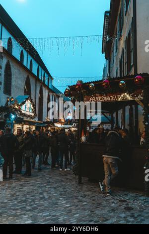 Bâle, Suisse - 5 décembre 2024 : marché de Noël traditionnel en soirée sur la Barfusserplatz avec lumières festives et cabines de rue et vis Banque D'Images