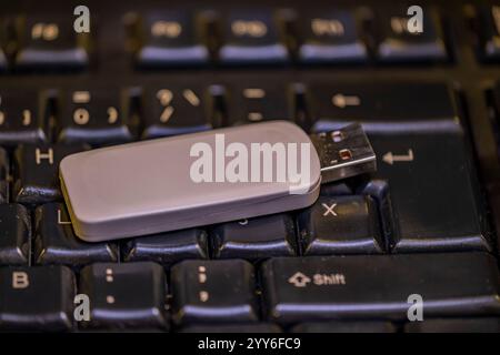 Une clé USB est installée sur un clavier. Le lecteur flash est blanc et possède un connecteur noir. Le clavier est noir et a quelques touches, y compris th Banque D'Images