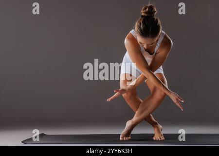 femme en vêtements de sport blancs pratiquant des poses de yoga complexes, étirements et formation de pilates, Banque D'Images